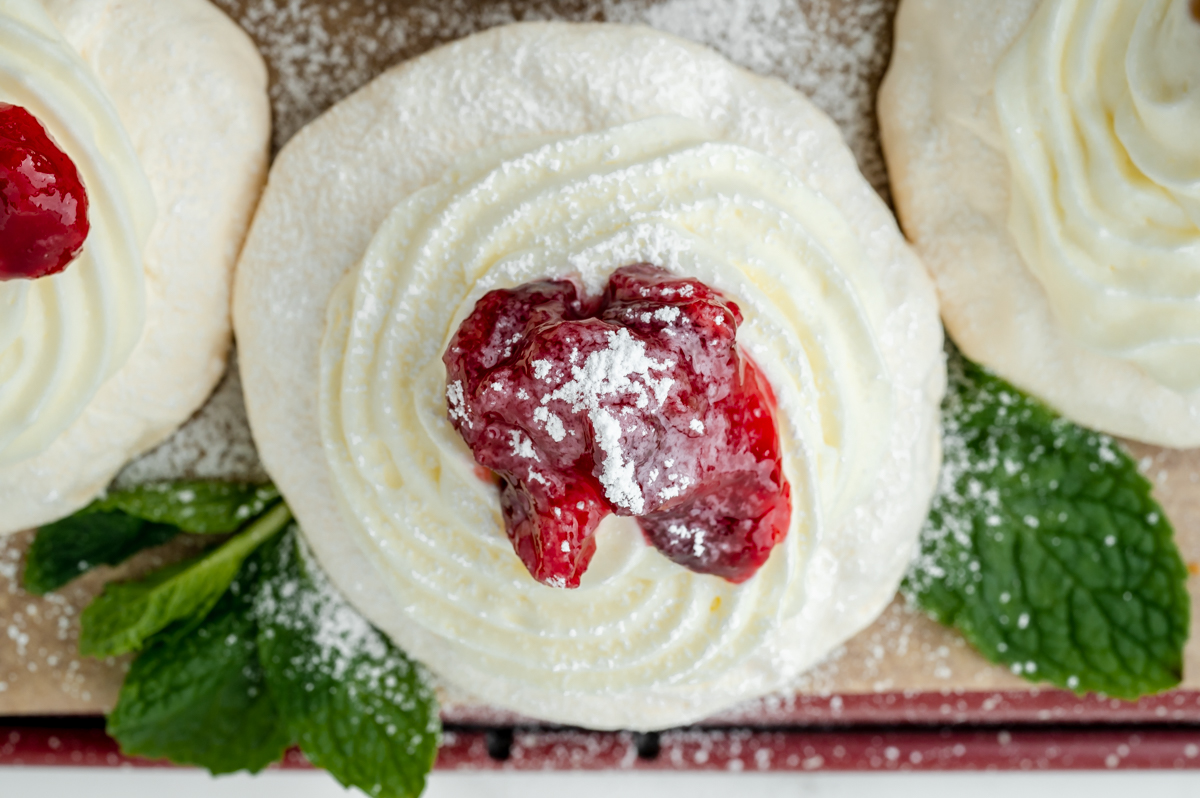 close up overhead shot of mini meringue topped with whipped cream and berries