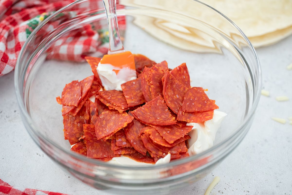 cream cheese, sour cream and pepperoni pieces in a bowl