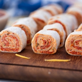 straight on shot of pizza pinwheels on wooden tray