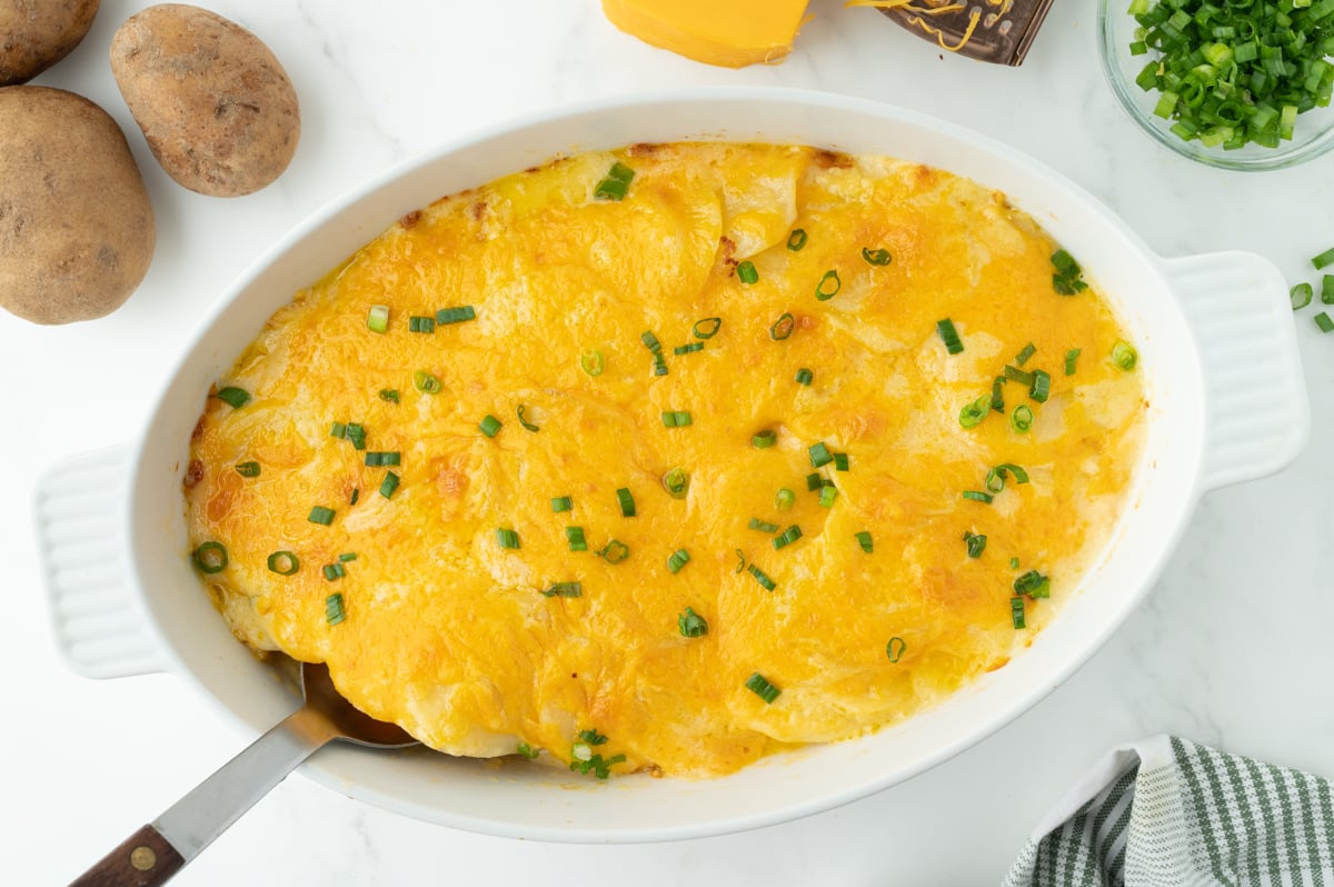 overhead shot of serving spoon in dish of au gratin potatoes