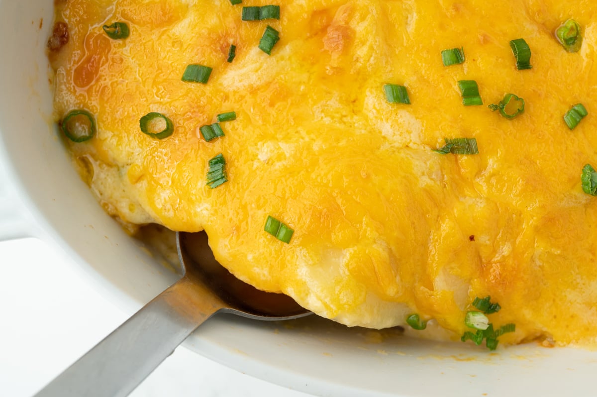 close up overhead shot of serving spoon in dish in au gratin potatoes