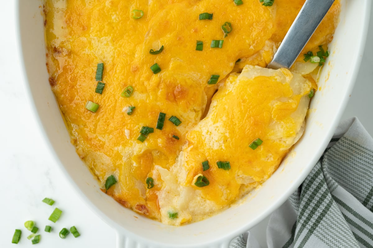 overhead shot of serving spoon in dish in au gratin potatoes