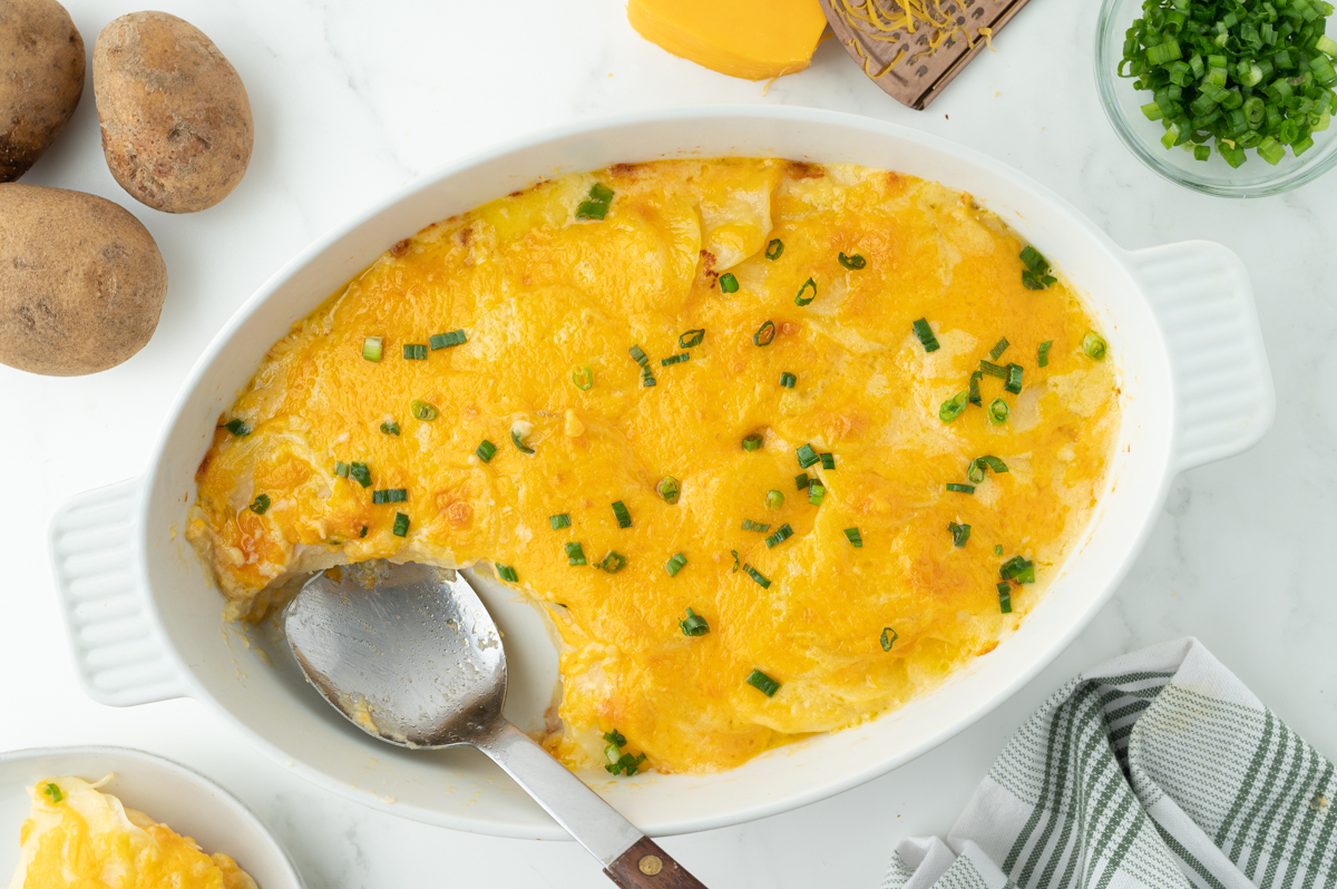 overhead shot of slice taken out of au gratin potatoes with serving spoon