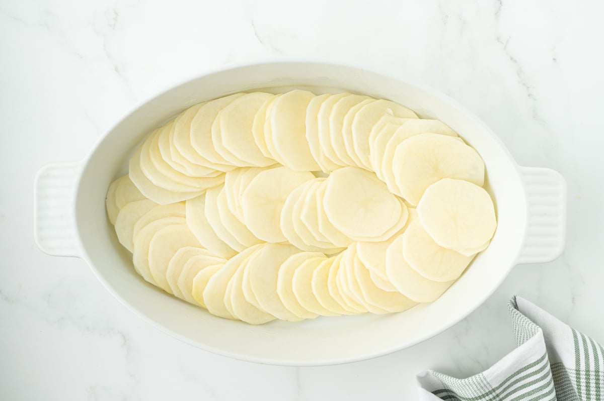 overhead shot of sliced potatoes in baking dish