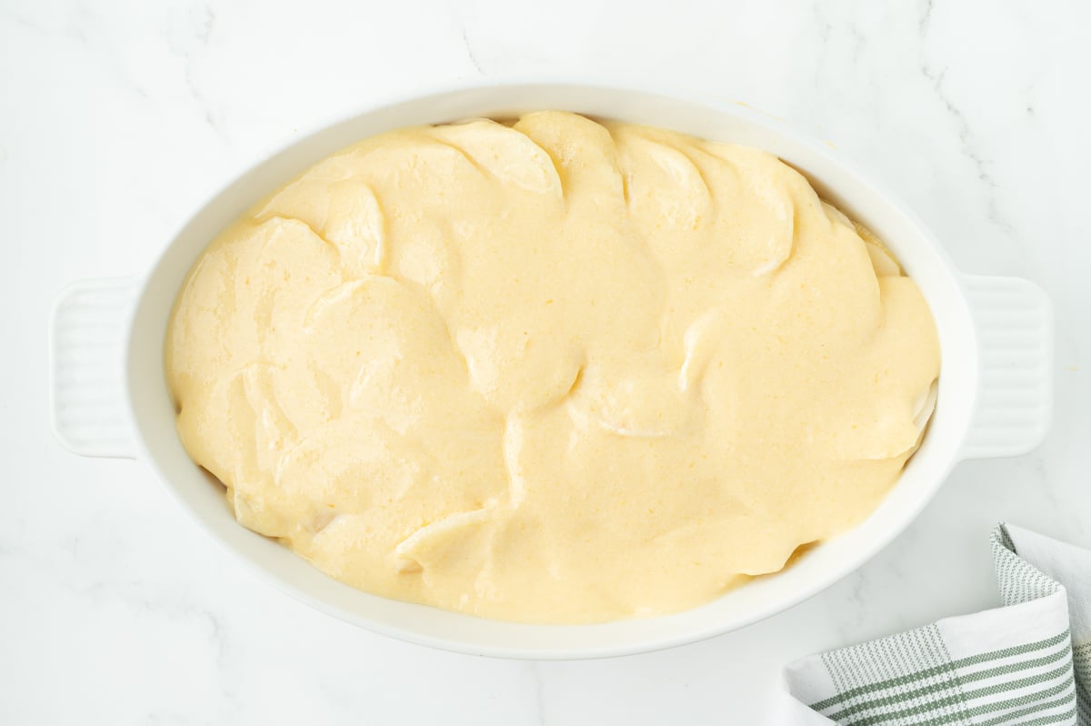 overhead shot of cheese sauce over sliced potatoes