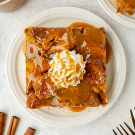 overhead shot of slice of pumpkin bread pudding topped with whipped cream and caramel