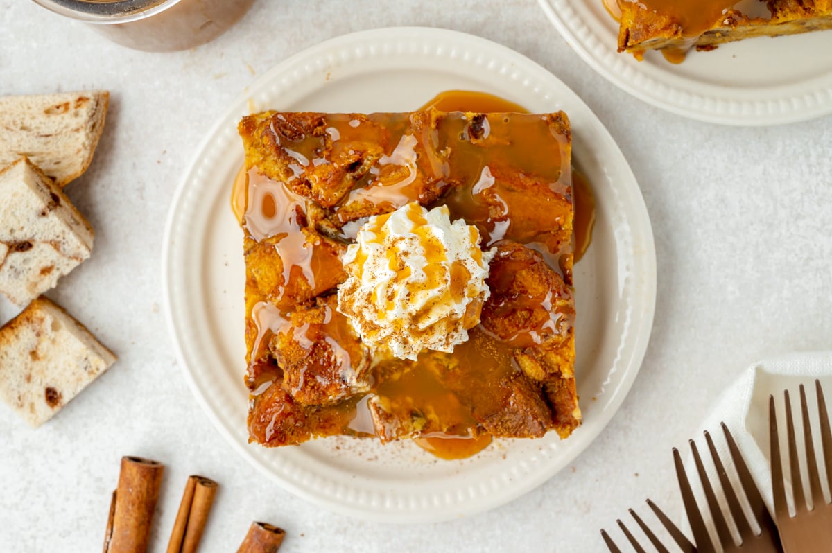 overhead shot of slice of pumpkin bread pudding topped with whipped cream and caramel