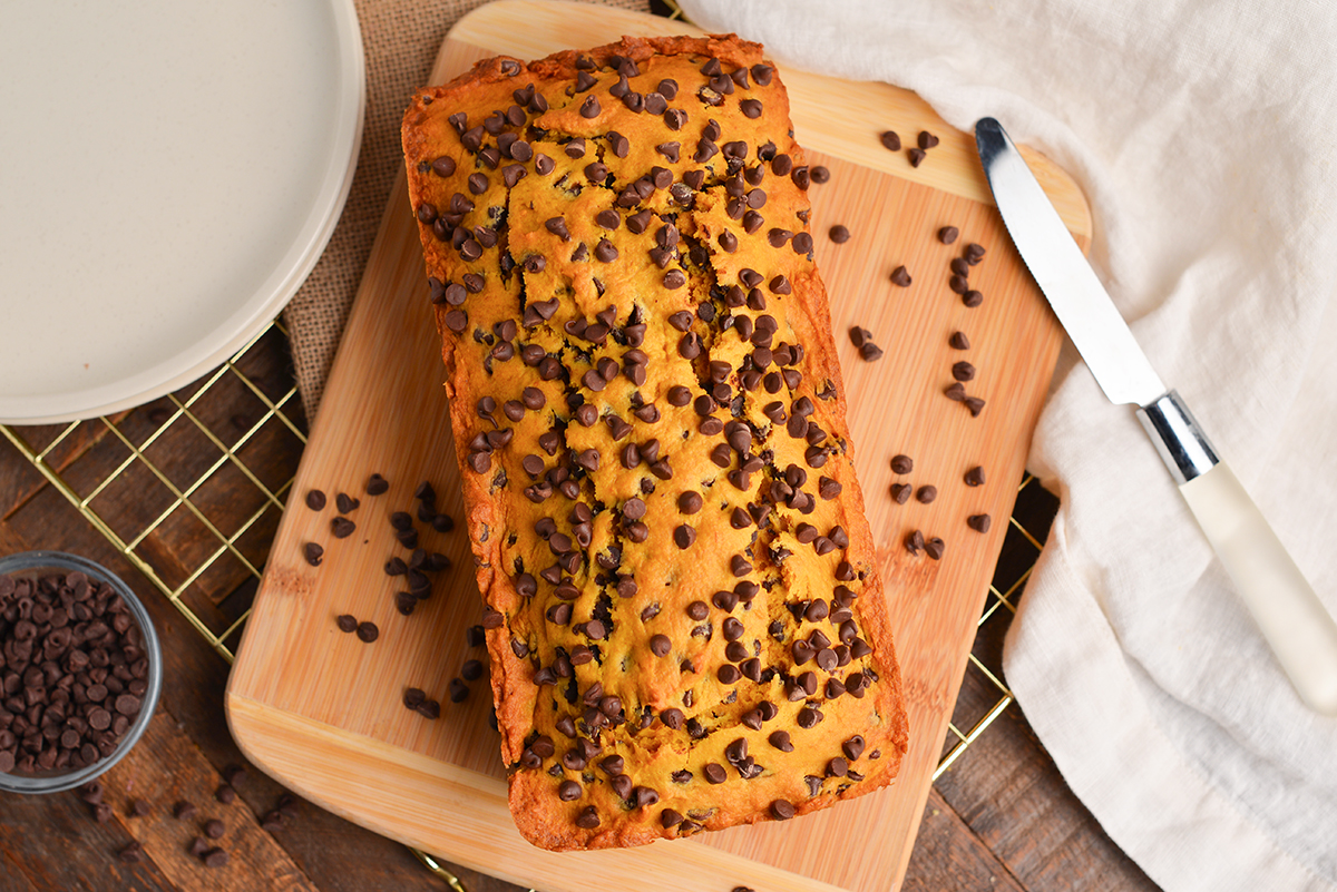 pumpkin chocolate chip bread with mini chocolate chips on a wood cutting board