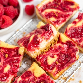 angle view of raspberry cheesecake bars on a wire rack
