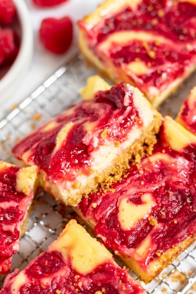 angle view of raspberry cheesecake bars on a wire rack