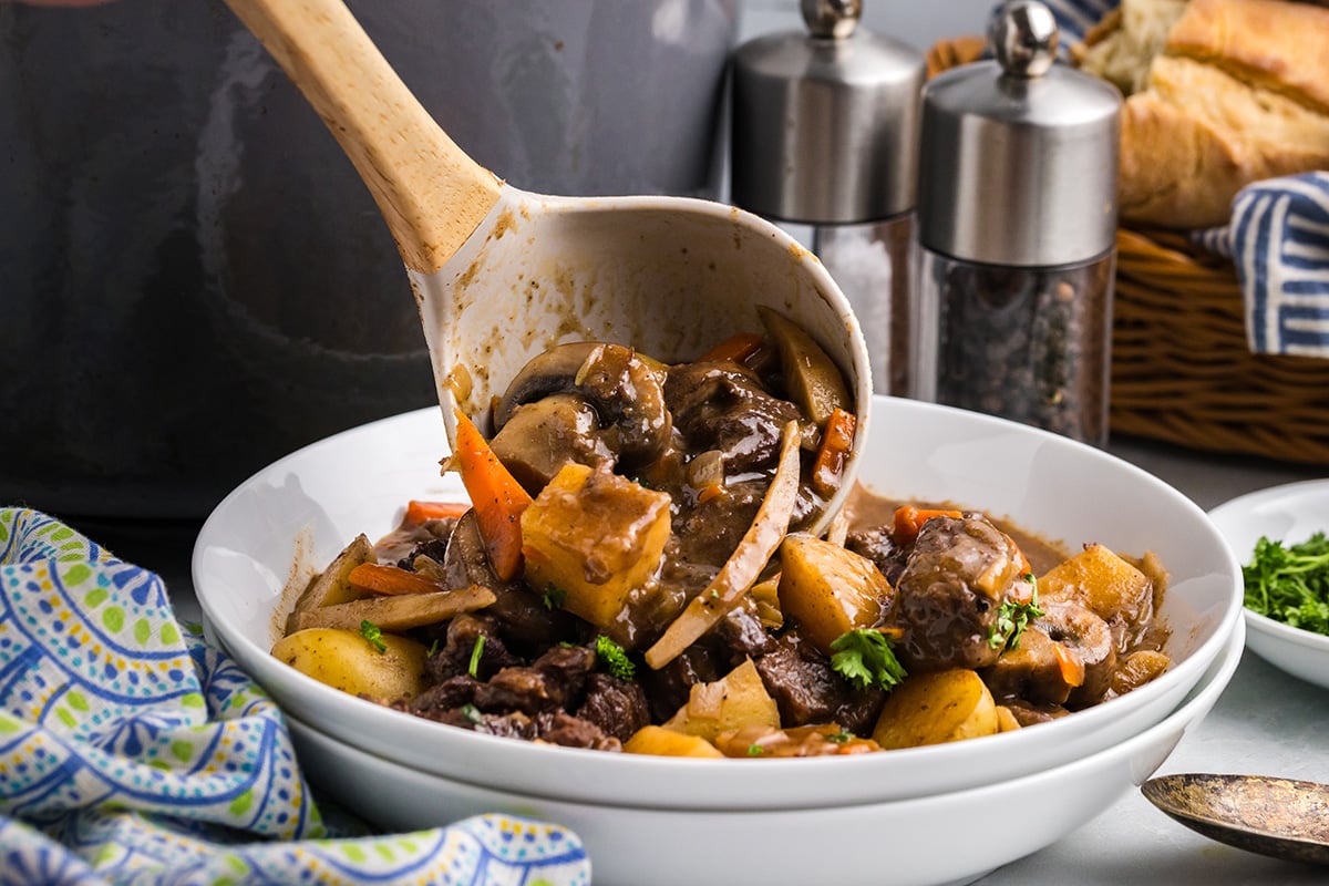 ladle added red wine beef stew to bowl