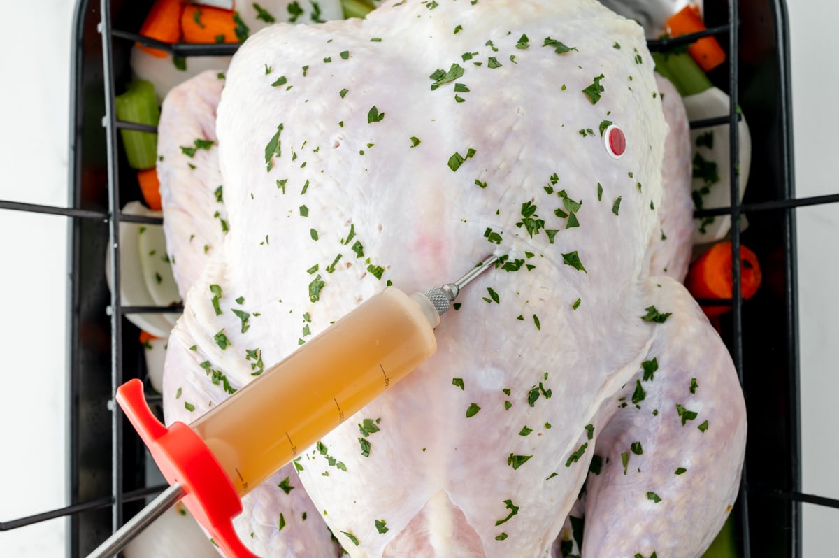 overhead shot of syringe adding injection to raw turkey