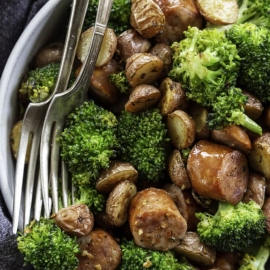 angled shot of bowl of sheet pan potatoes, broccoli and sausage
