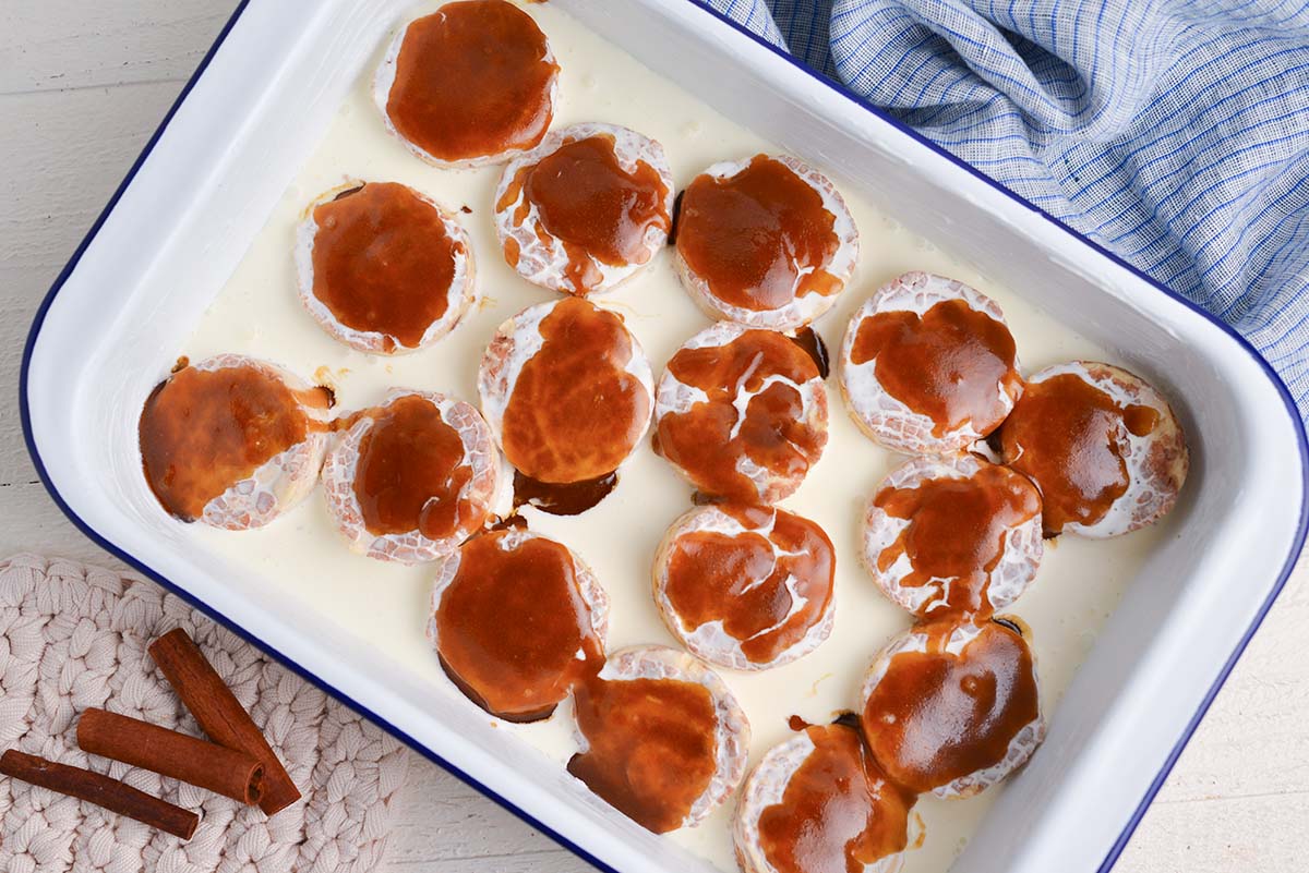caramel sauce poured over raw cinnamon rolls in baking dish