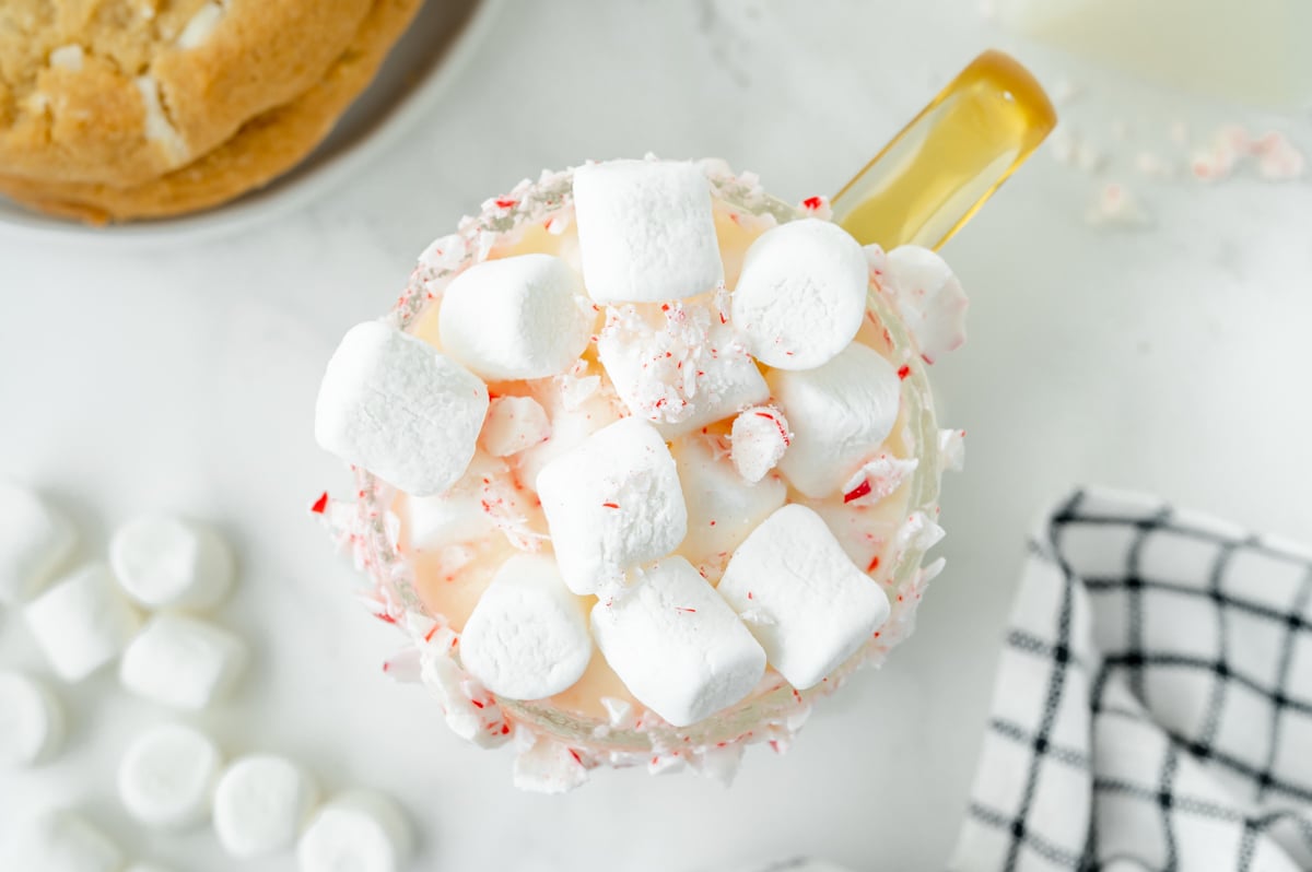 overhead shot of mug of white hot chocolate topped with marshmallows and peppermint