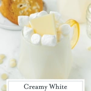 angled shot of mug of white hot chocolate with text overlay for pinterest