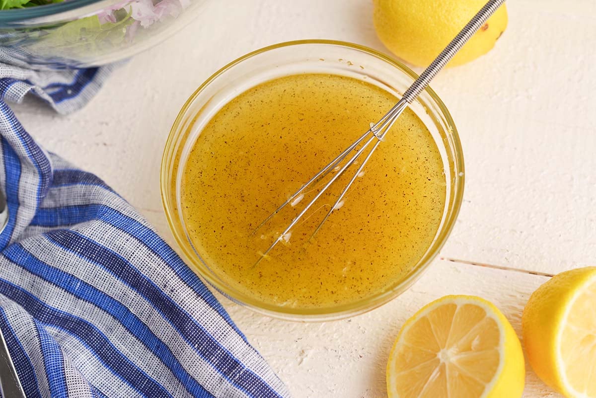 angled shot of dressing in bowl with whisk