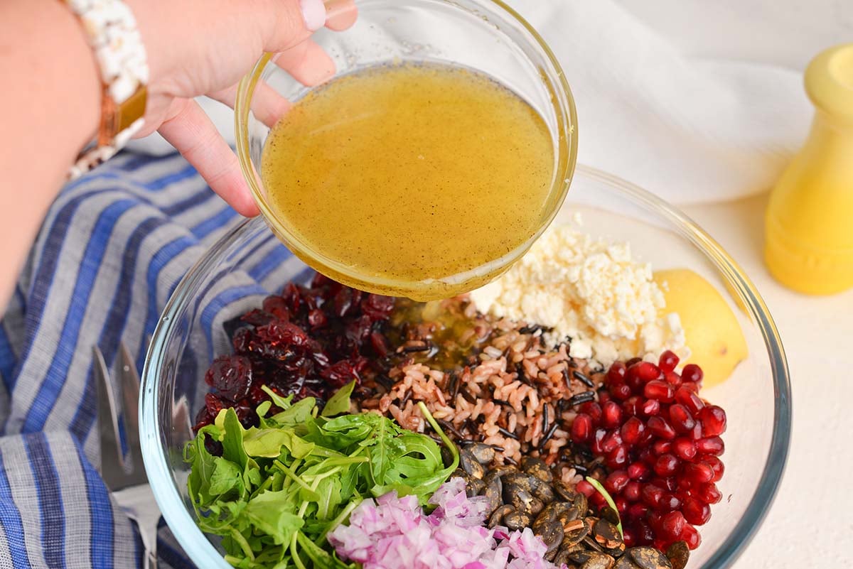 hand pouring dressing into salad