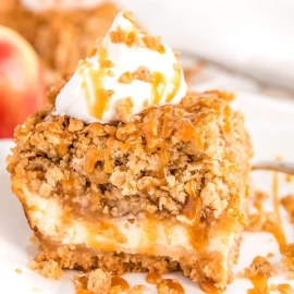 angled shot of apple cheesecake bar on plate topped with whipped cream