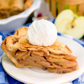 angled shot of slice of apple pie topped with ice cream on plate