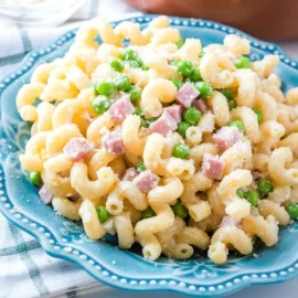 angled shot of ham pasta on blue plate