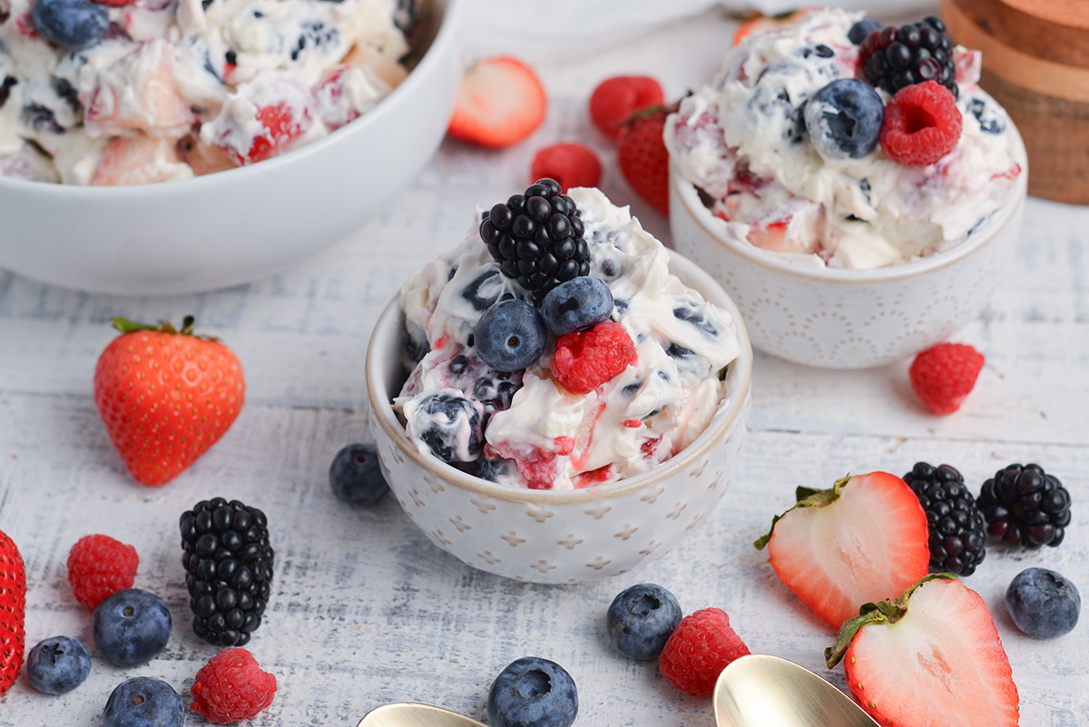 angled shot of three bowls of berry cheesecake salad