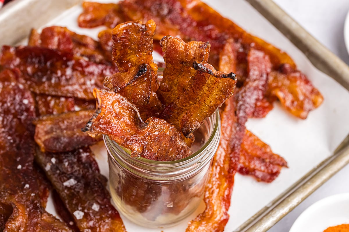 overhead shot of candied bacon in jar placed on baking sheet