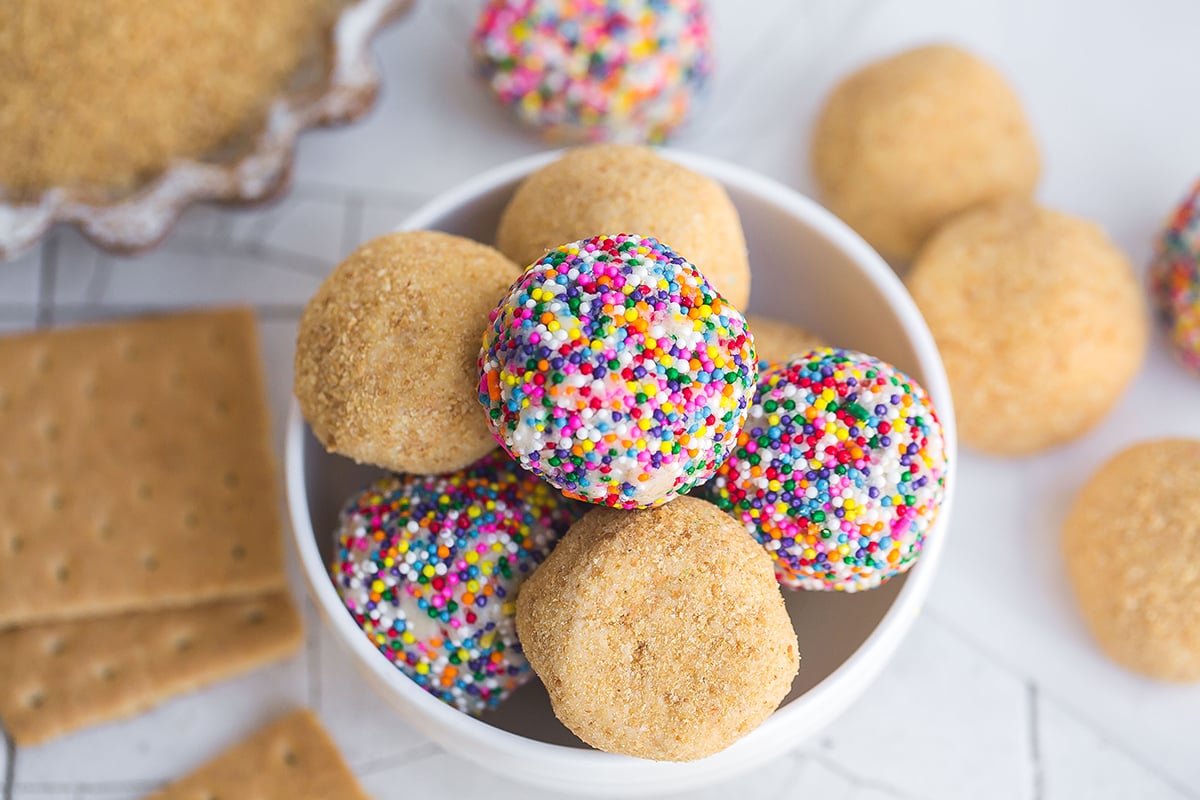bowl of cheesecake balls with sprinkles and graham cracker crumbs