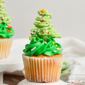 close up of a chocolate christmas tree on top of a green frosted cupcakes