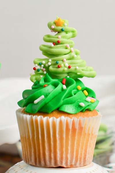 close up of a chocolate christmas tree on top of a green frosted cupcakes