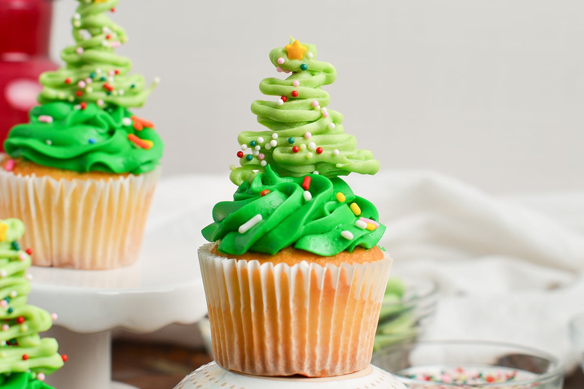 close up of a chocolate christmas tree on top of a green frosted cupcakes