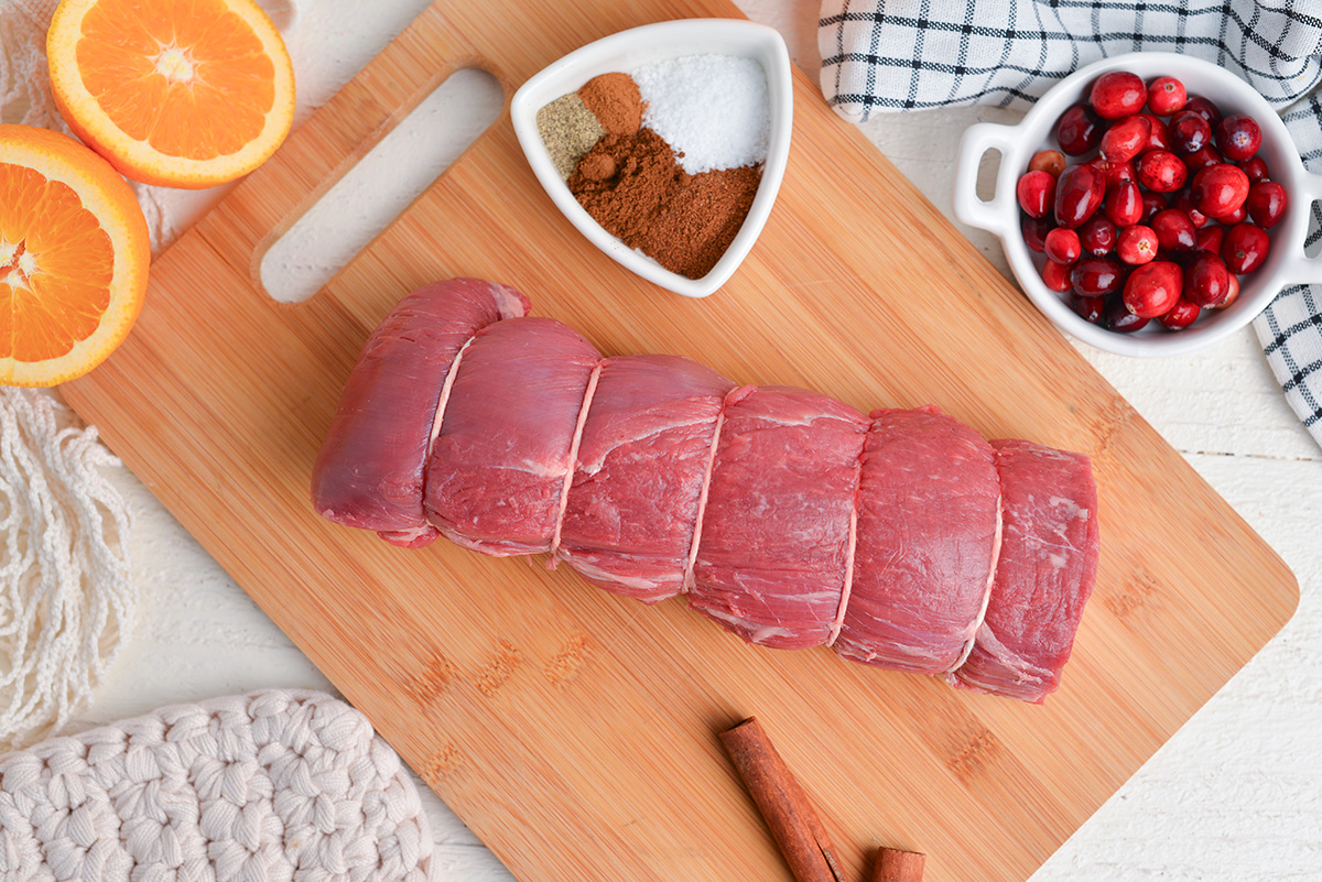 tied beef tenderloin roast on a wood cutting board