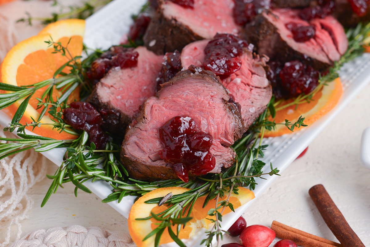 close up of carved beef with sauce on a serving platter