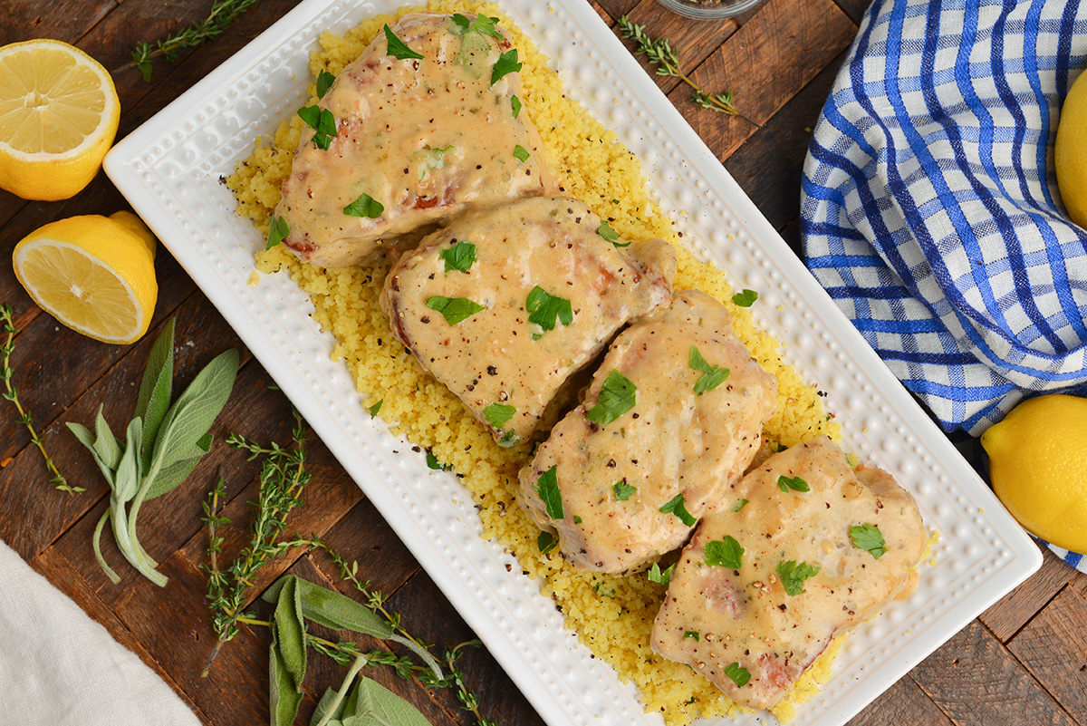overhead of porks chops on top of couscous with fresh herbs and a blue linen