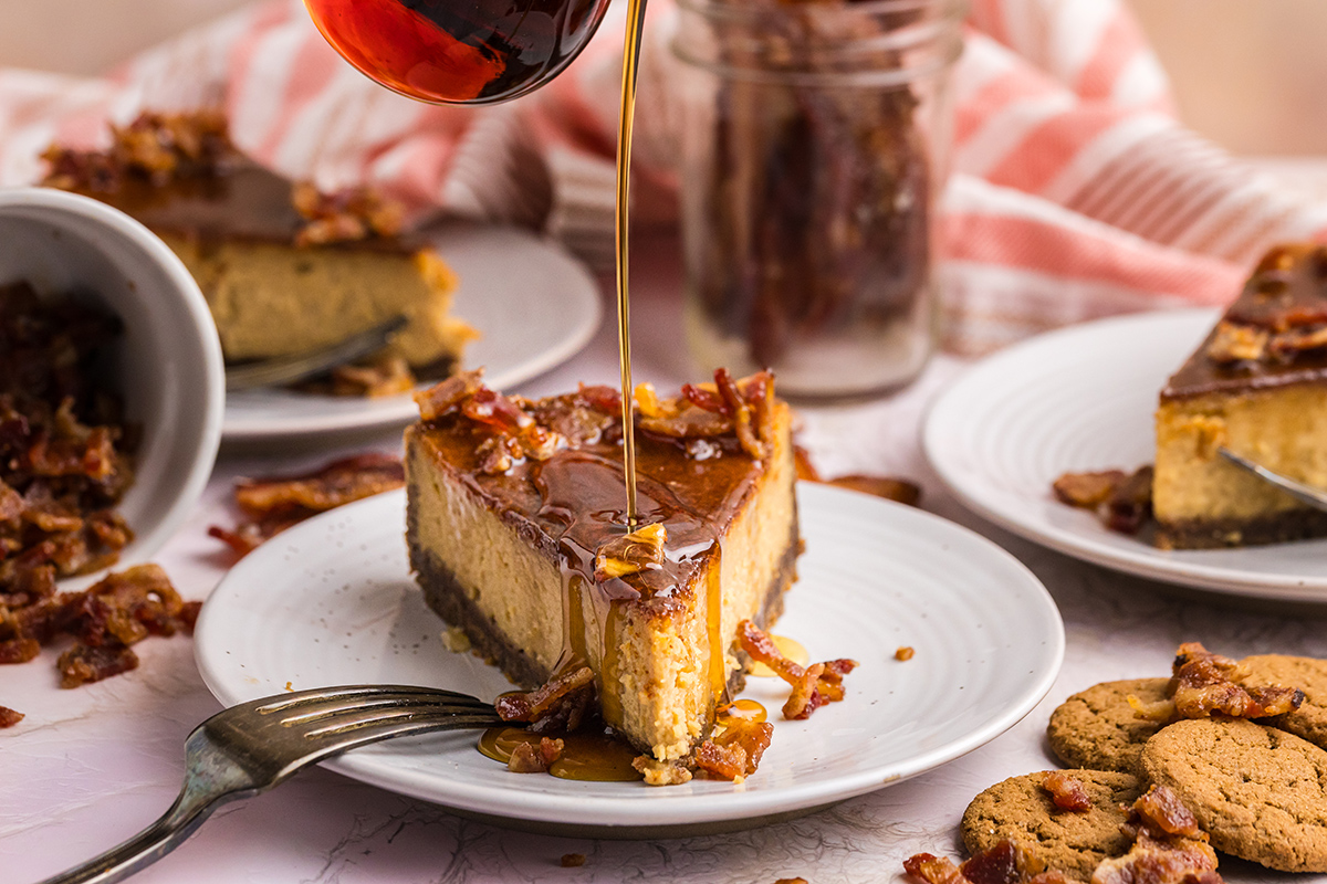 straight on shot of syrup poured onto slice of maple cheesecake