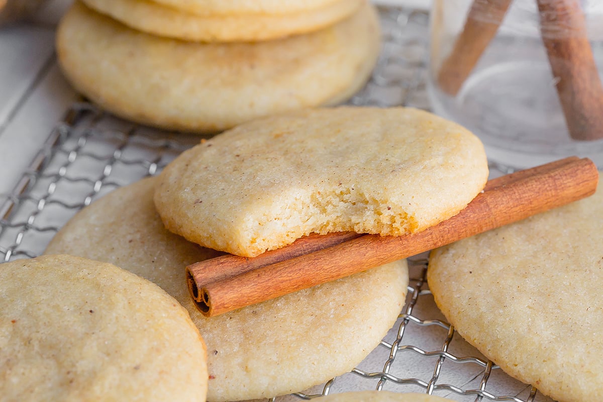 small sugar cookie with a bite taken out settling on a cinnamon stick