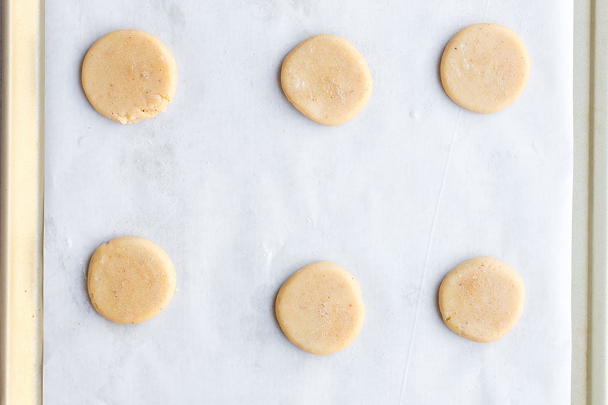 flattened cookies on a parchment lined baking sheet