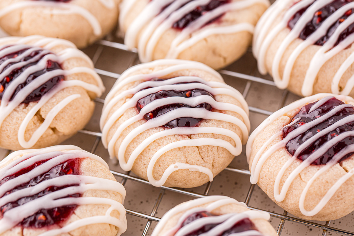 close up angled shot of raspberry thumbprint cookies on cooling rack