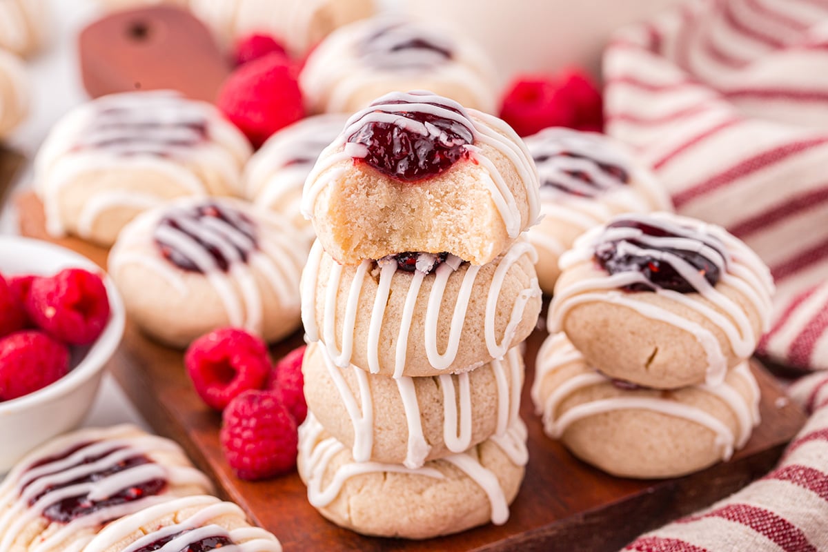 bite taken out of stack of raspberry thumbprint cookies