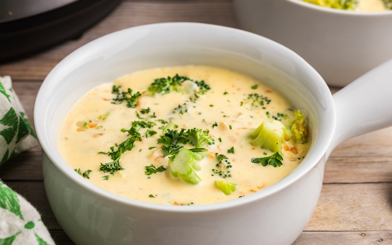 white bowl of creamy cheddar soup with broccoli