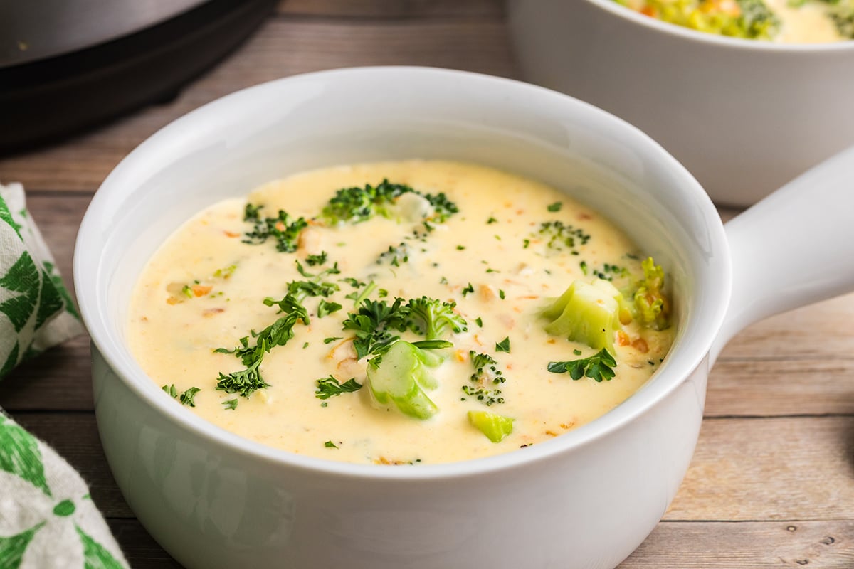 white bowl of creamy cheddar soup with broccoli