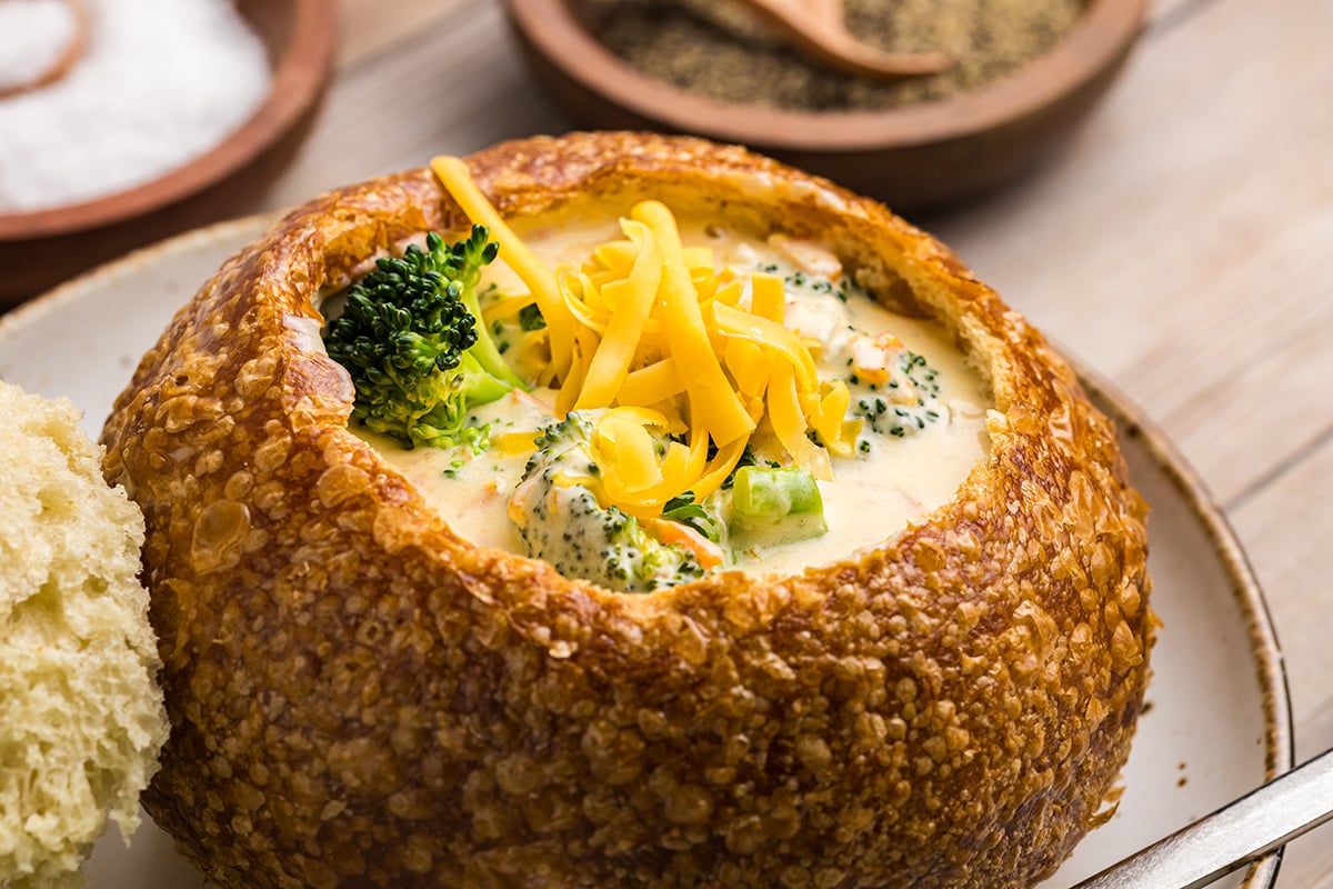 soup in a bread bowl topped with shredded cheddar cheese