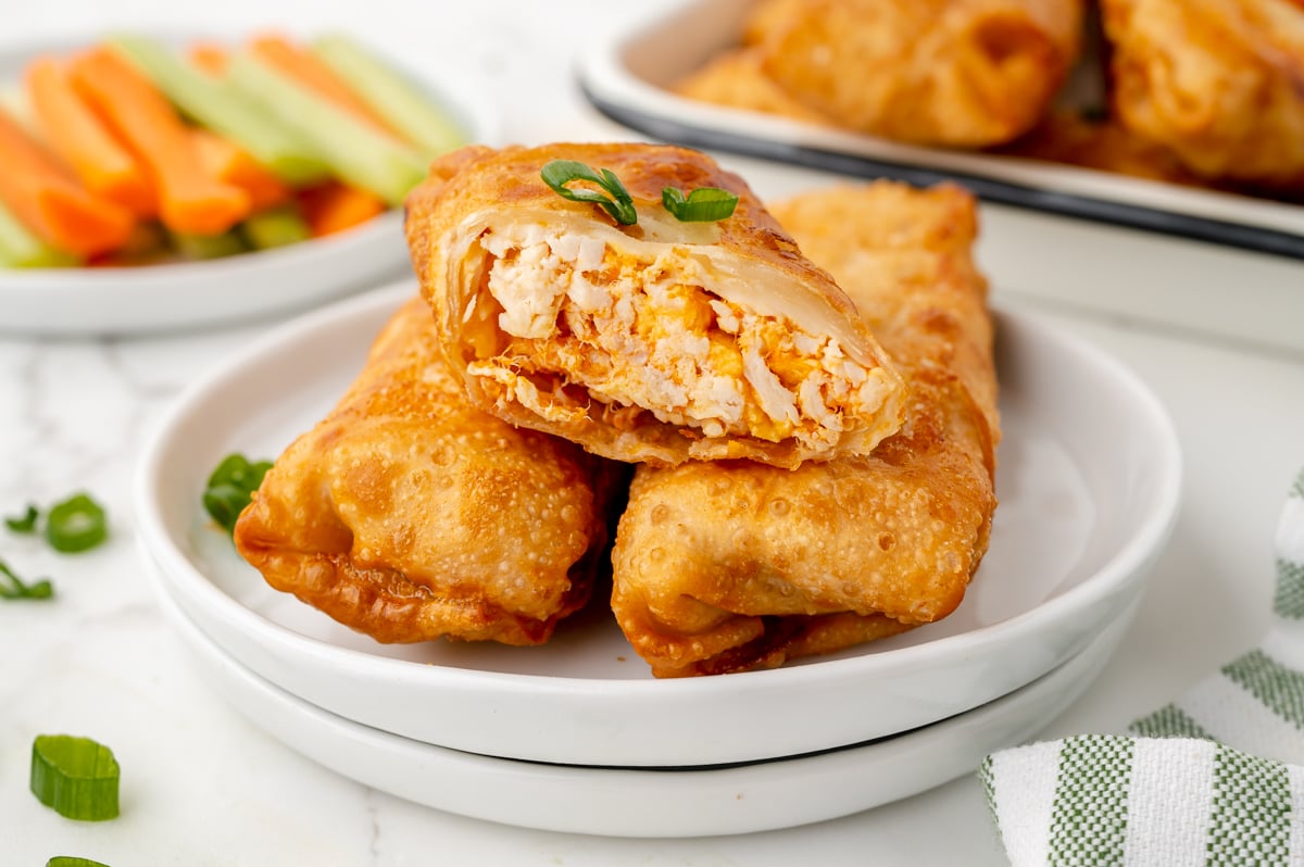 angled shot of three buffalo chicken egg rolls on plate