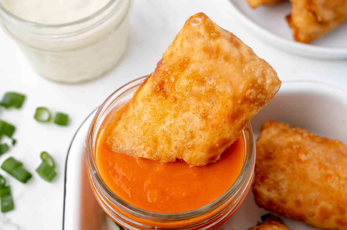 egg roll dipping into jar of buffalo sauce