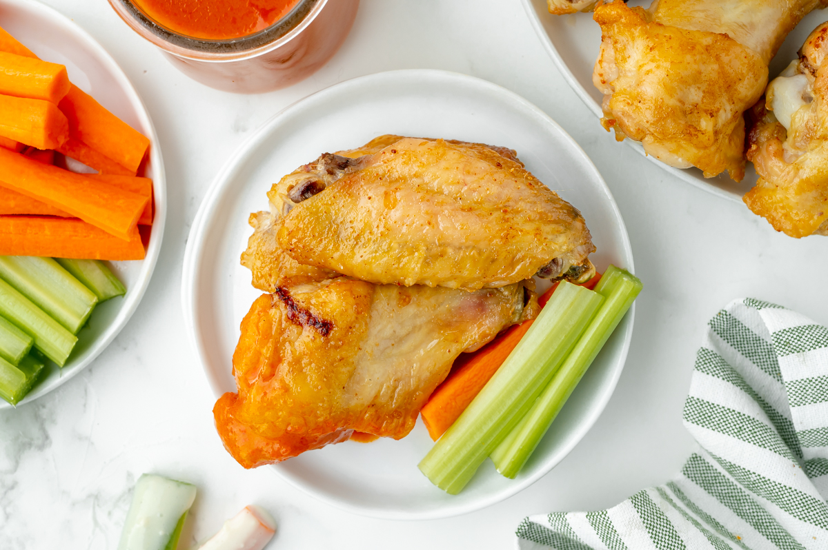 overhead shot of two chicken wings on plate with carrot and celery