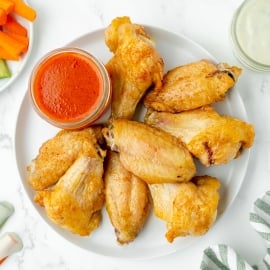 overhead shot of plate of baked buffalo wings with sauce