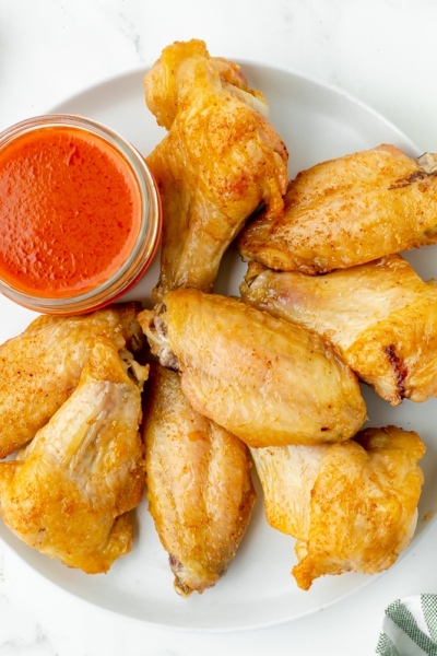 overhead shot of plate of baked buffalo wings with sauce