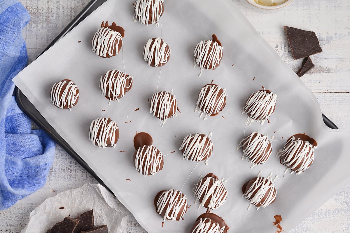 overhead shot of white chocolate drizzled onto chocolate cheesecake bites