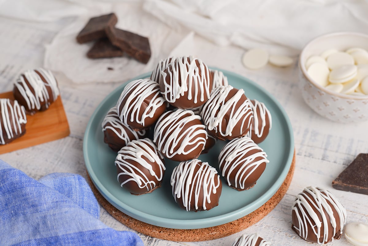 angled shot of chocolate cheesecake bites stacked on blue plate