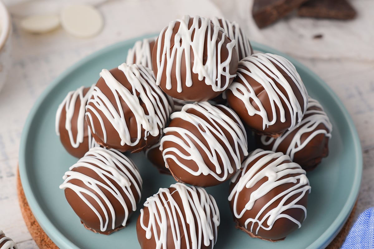 close up angled shot of chocolate cheesecake bites stacked on blue plate